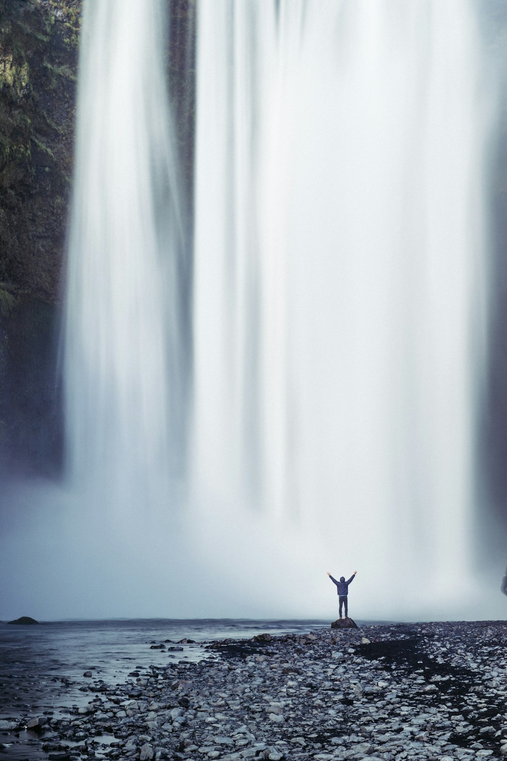 Person, die neben dem Wasserfall steht