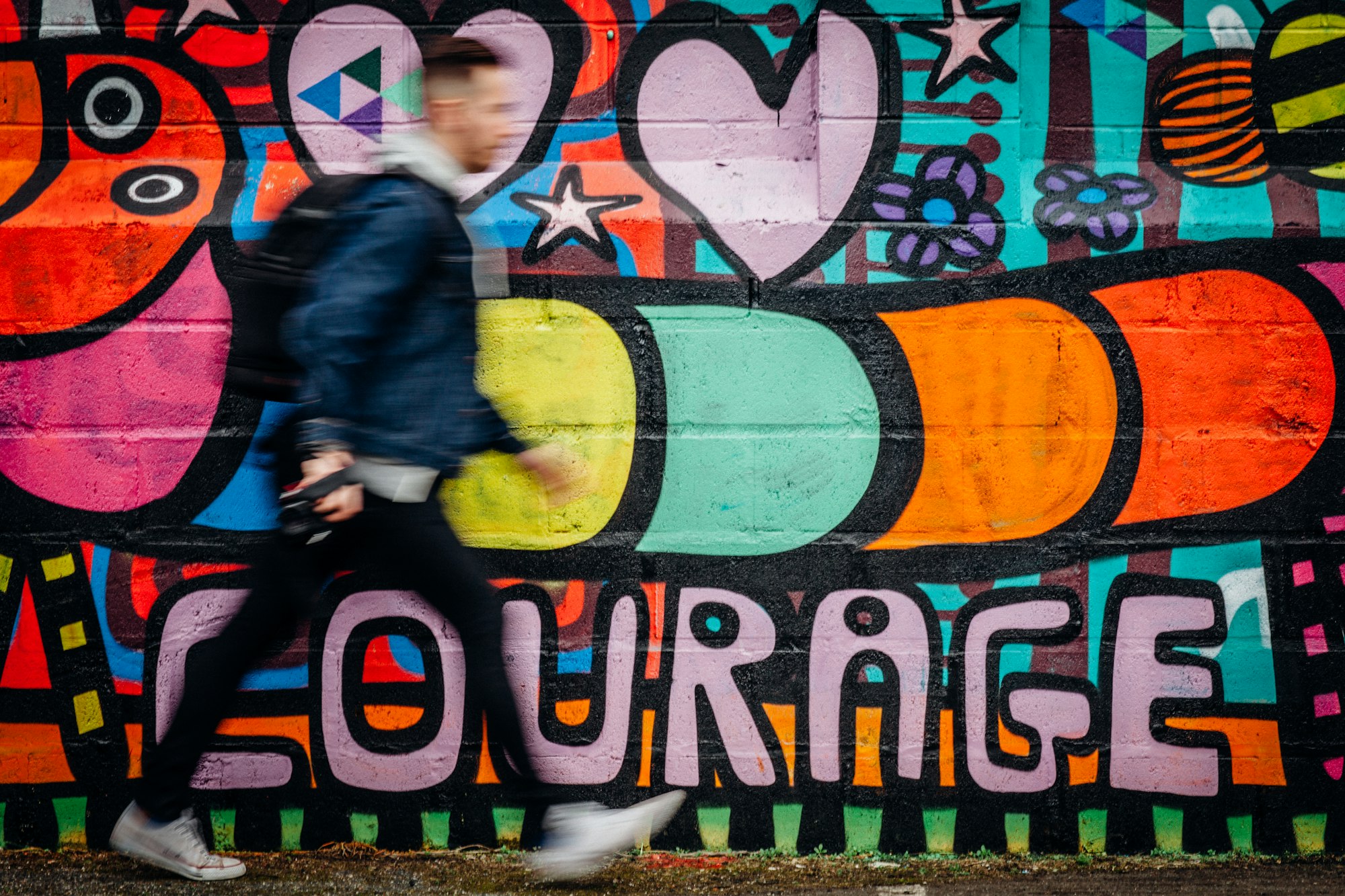 Courage wall art with man walking past it