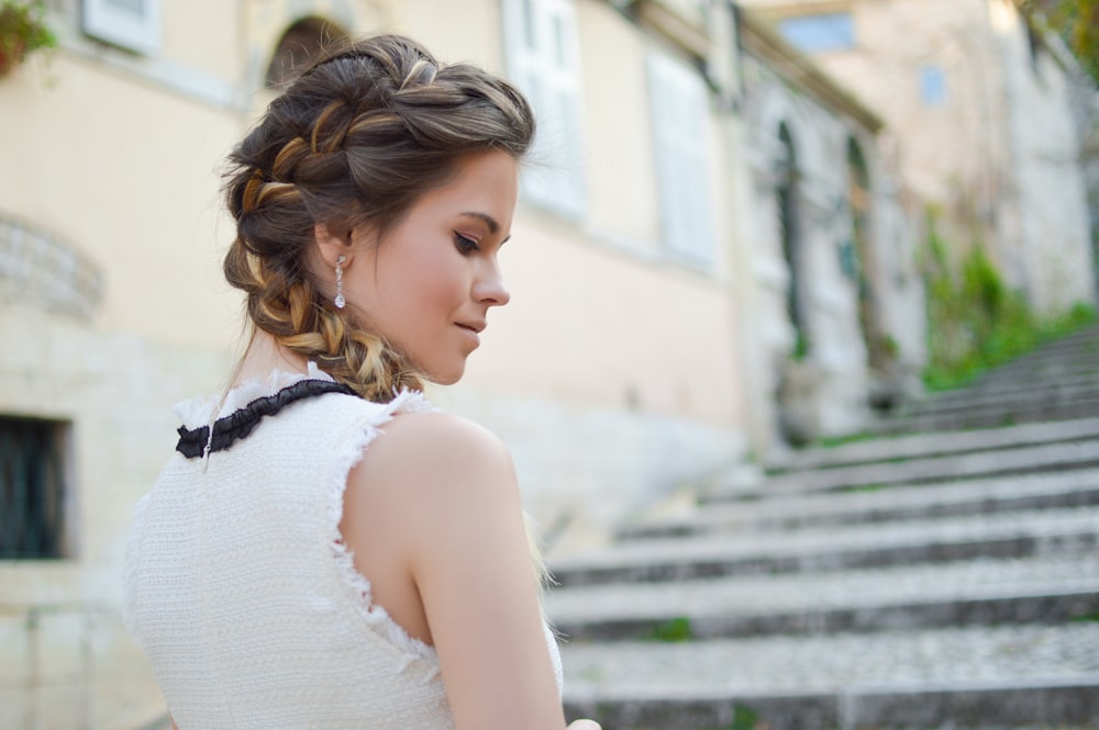Woman with a french braid hairstyle smiling on a staircase