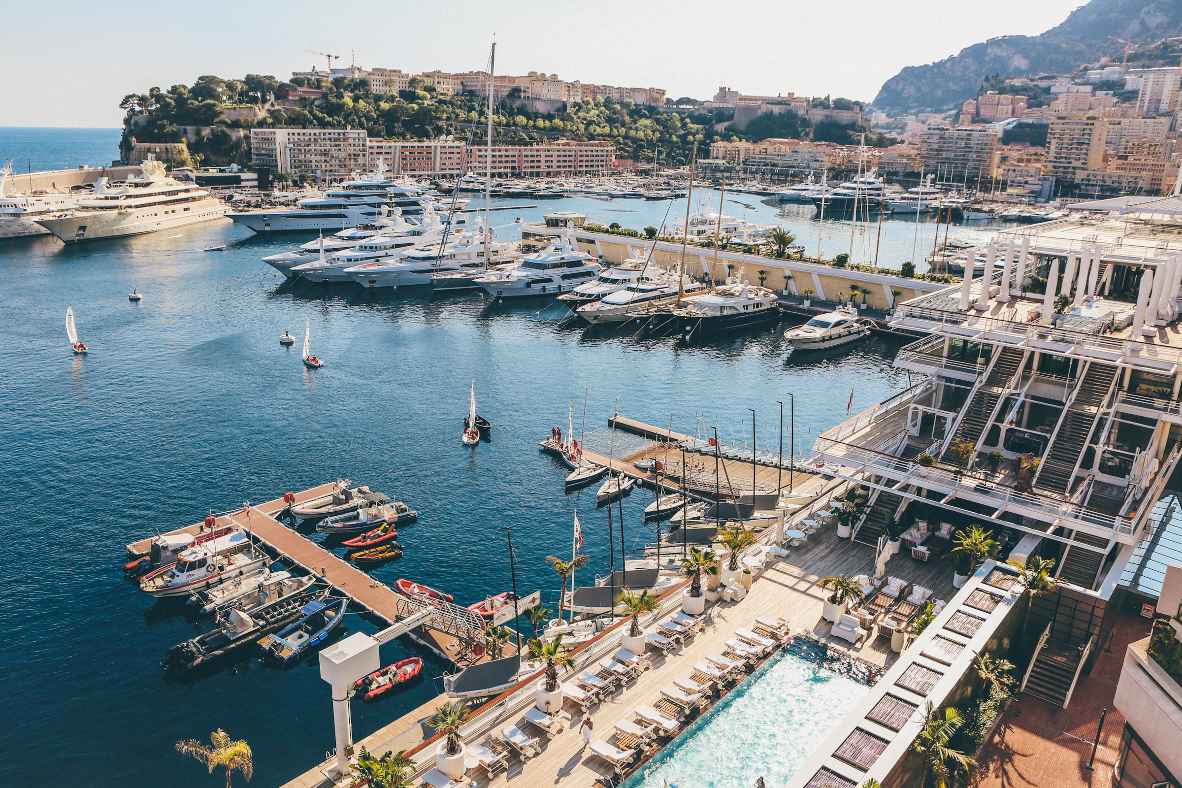 Aerial view of Port Hercule, Monaco: yachts moored in blue water beside the harbourside section of the circuit
