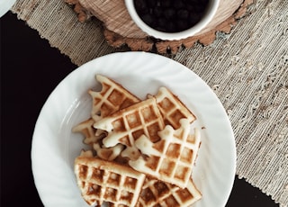 photo of waffles beside bowls of strawberries, banana, and black berries