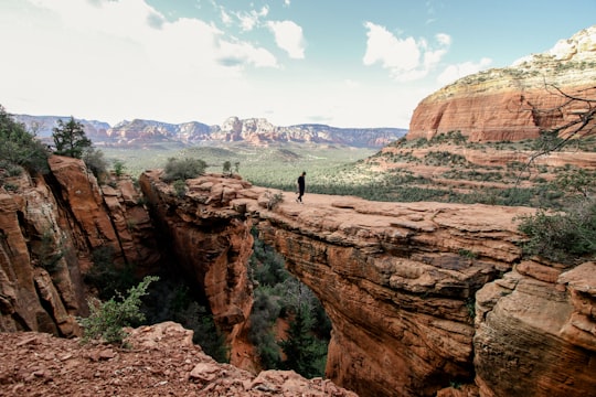 person standing on brown rock formation during daytime in Coconino National Forest United States