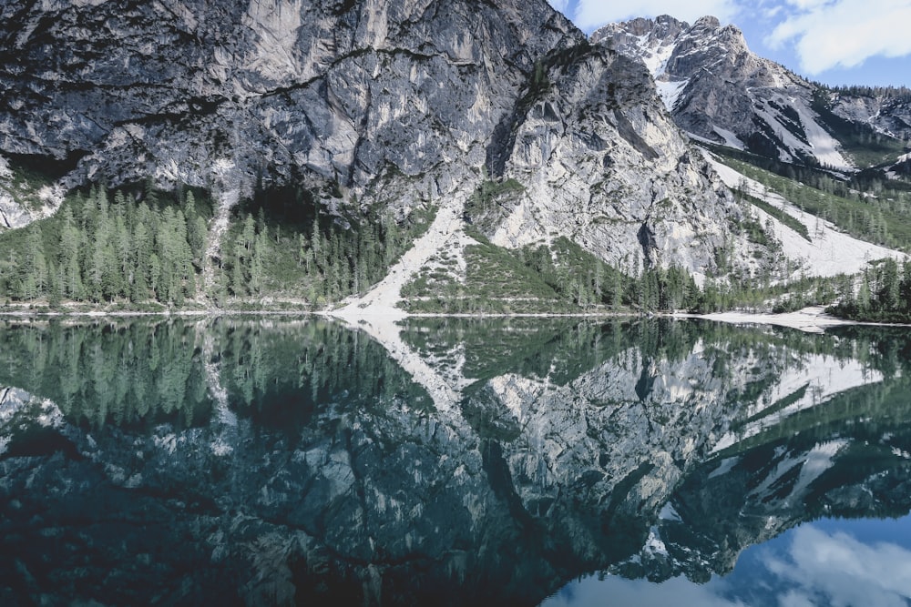 gray rocky mountain beside lake during daytime