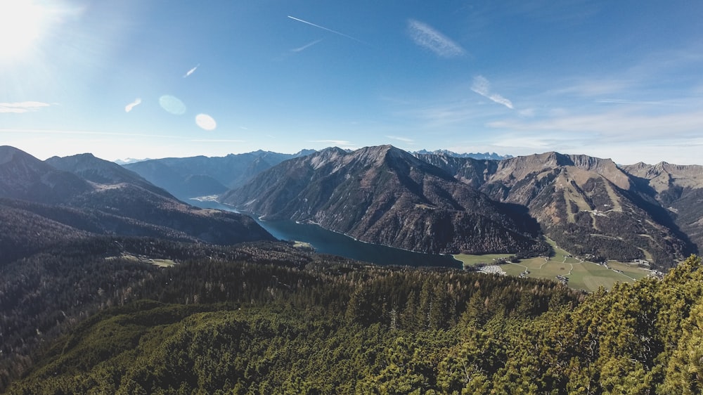 green trees and mountains under blue sky during daytime