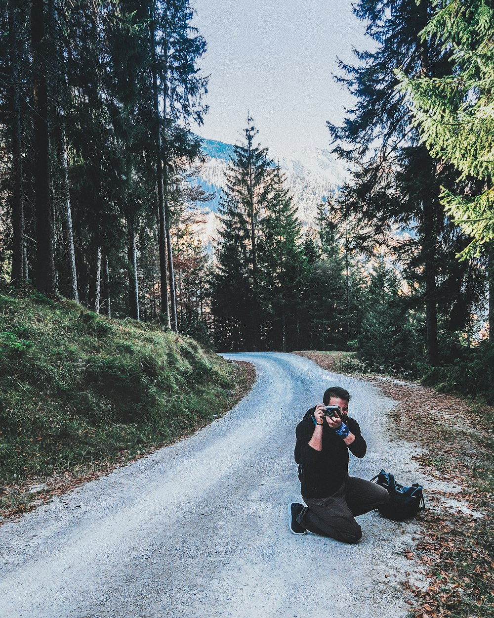 man in black jacket and black pants sitting on road during daytime