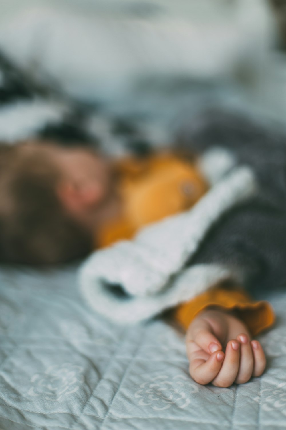 Um bebê está dormindo em uma cama com um ursinho de pelúcia