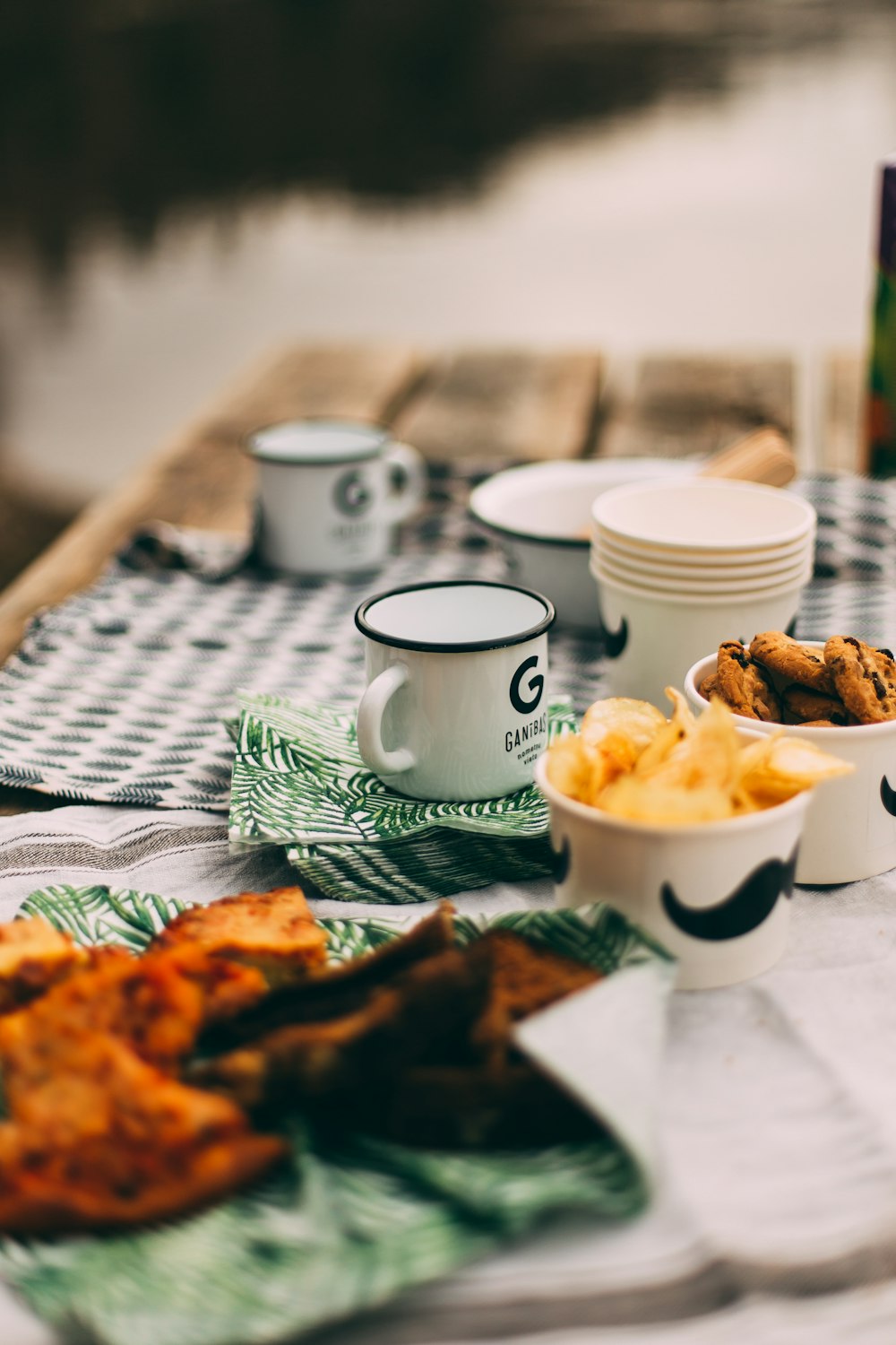 enamel-coated mugs and plastic cups on table selective focus photography