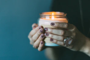 Close-up of hands holding recycled materials ready for crafting into candle vessels.