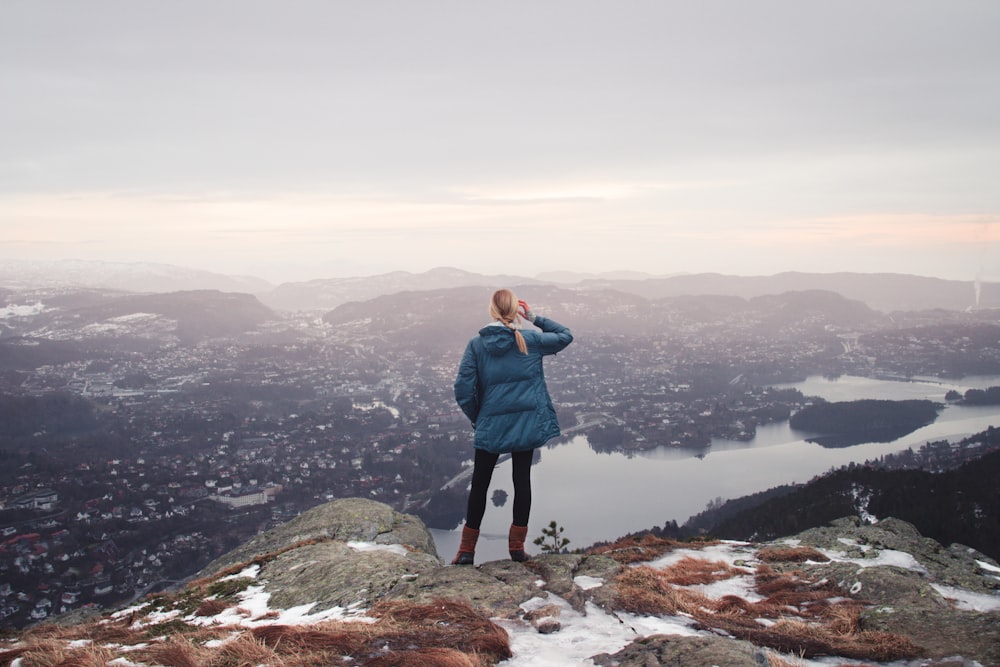 woman standing on cliff near body of water during daytime