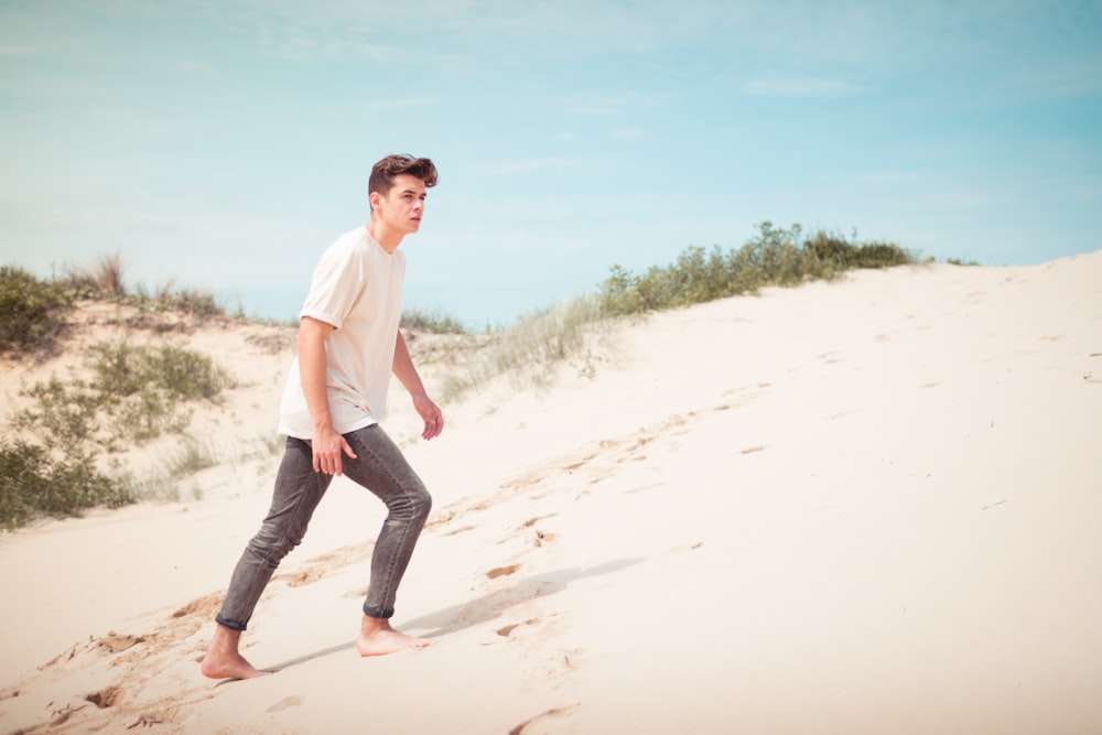 homem vestindo camiseta branca em pé no campo de areia durante o dia