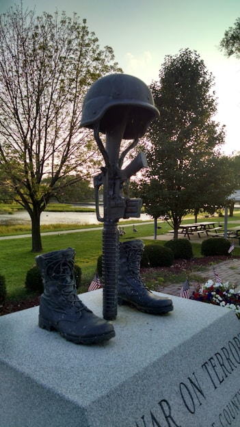A weathered combat helmet resting on a dusty ridge at sunset, symbolizing sacrifice and memory.