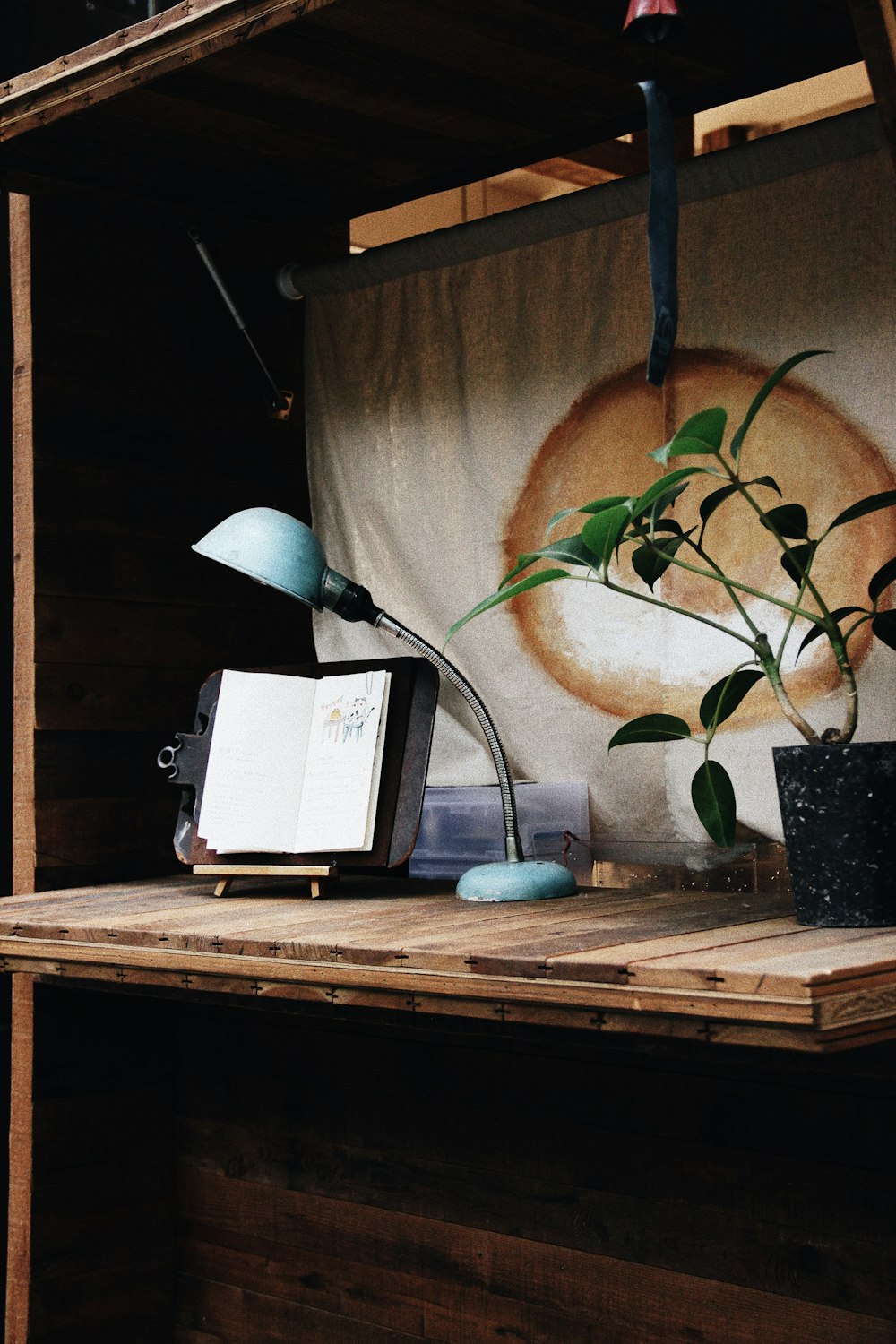 teal study lamp beside black wooden note book with black stand