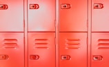 Close-up of a steel locker door with a glowing neon orange digital biometric lock, showcasing a brushed metal finish.