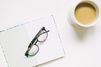 A pair of teyes sunglasses placed beside a leather-bound notebook and coffee cup, evoking a stylish daily routine.