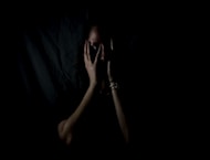 woman holding her face in dark room