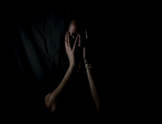 woman holding her face in dark room