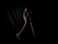 woman holding her face in dark room