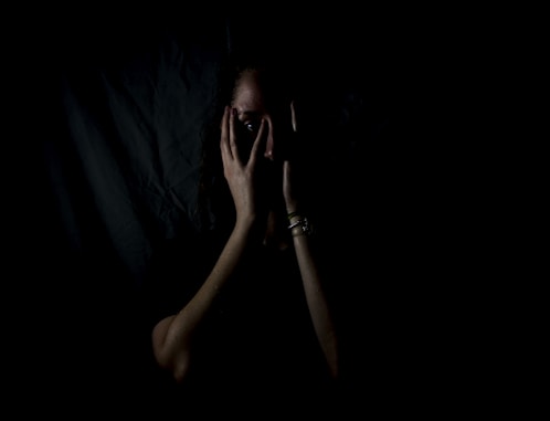 woman holding her face in dark room