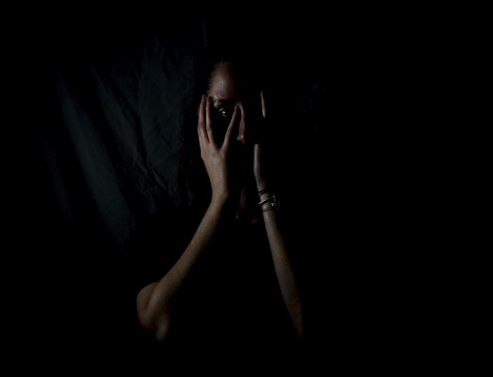 woman holding her face in dark room