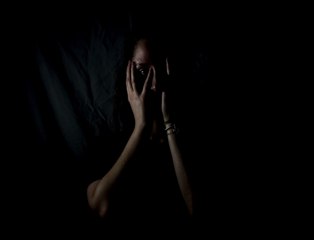 mulher segurando seu rosto no quarto escuro