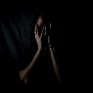 woman holding her face in dark room