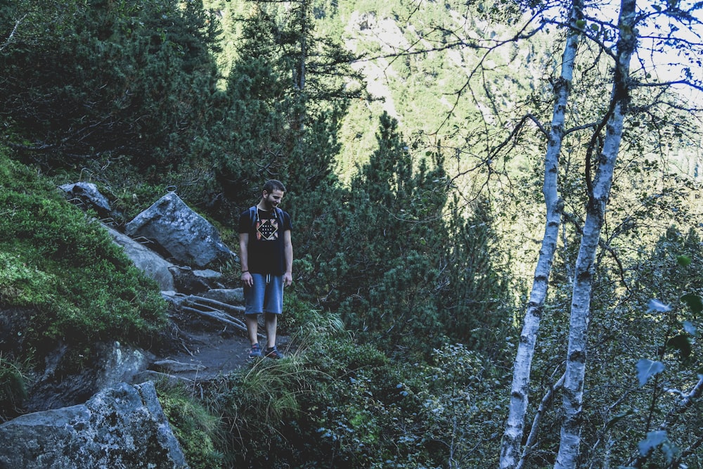 woman in black shirt and blue denim shorts standing on rocky hill during daytime