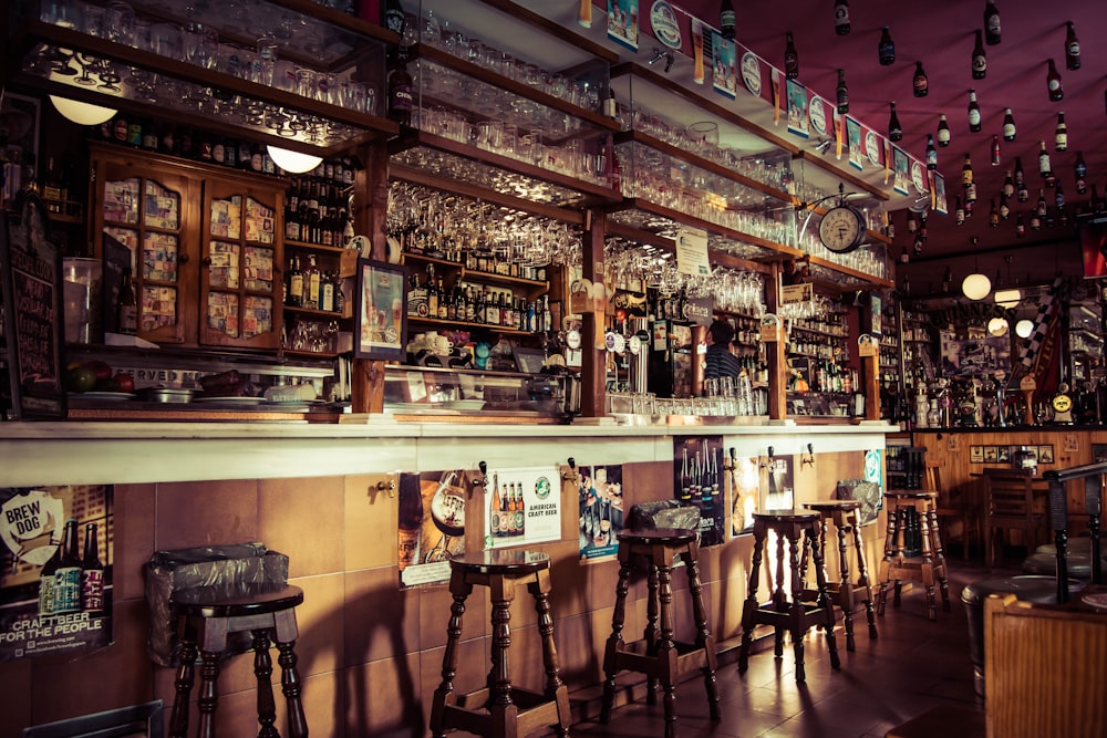 The interior of a bar with stools, glass cups and empty bottles attached to the roof in Madrid