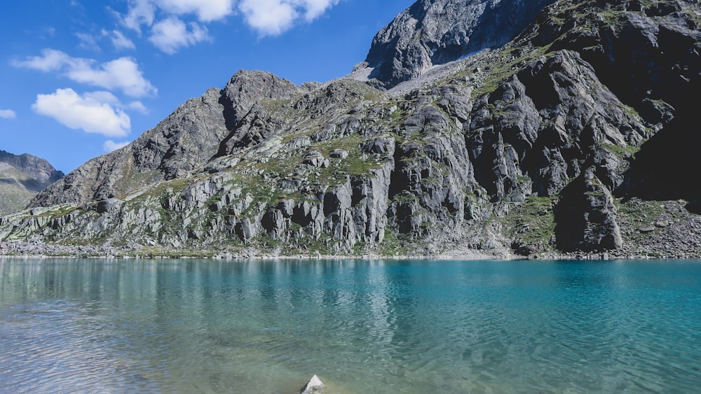 green and gray mountain beside body of water during daytime