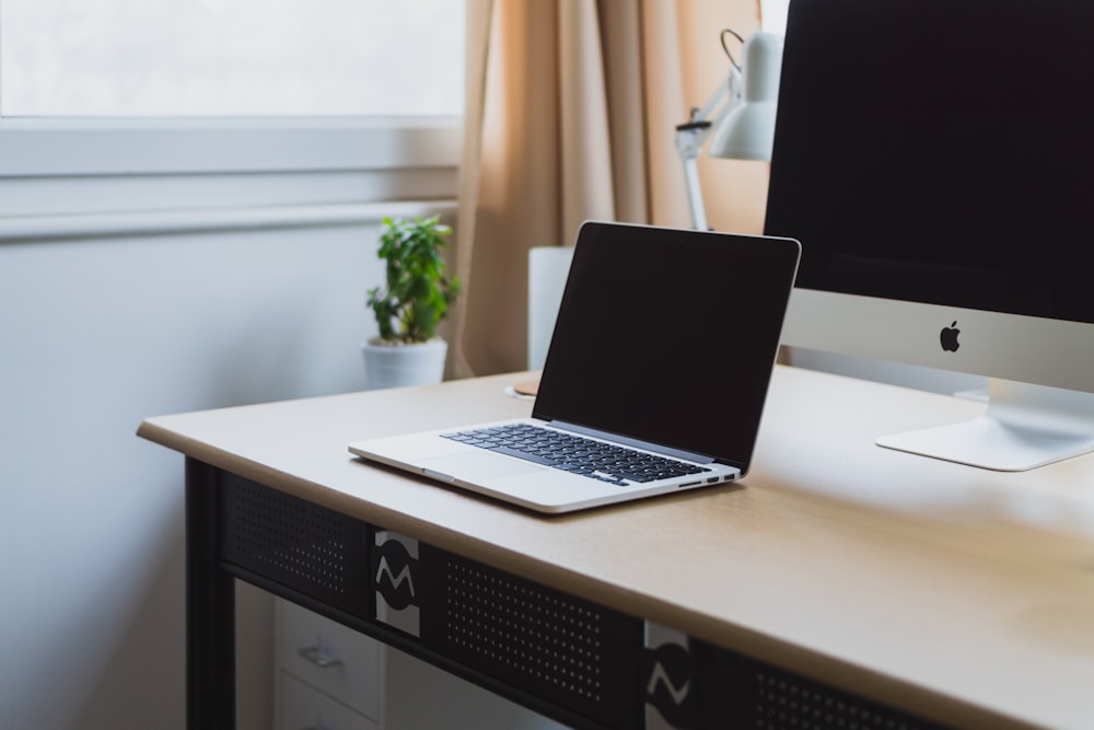 silberner Laptop auf dem Schreibtisch neben silbernem iMac