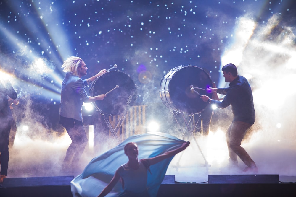 woman dancing in front of men playing drums on stage