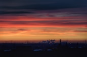 Sunset view of oil refinery with glowing lights and active pipelines.
