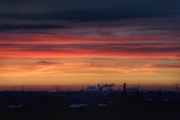 Sunset view of oil refinery with glowing lights and active pipelines.