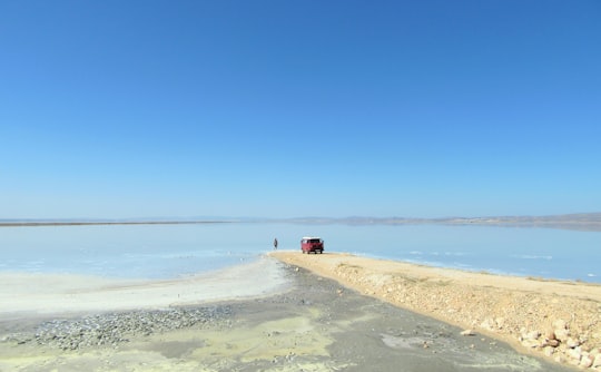 man standing near body of water and red car during daytime in Lake Tuz Turkey