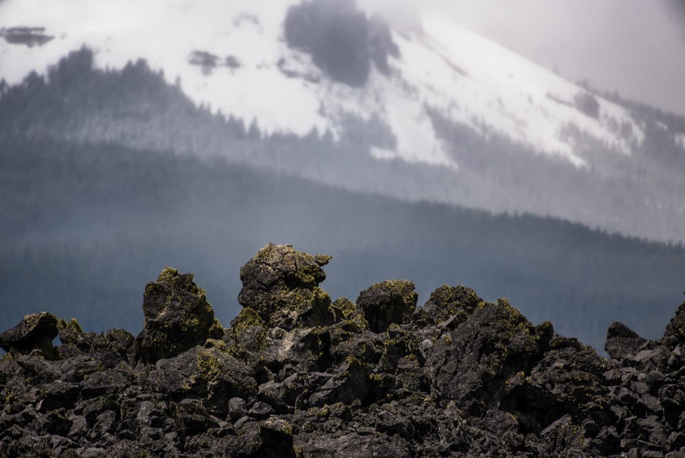 a mountain covered in rocks with a snow covered mountain in the background