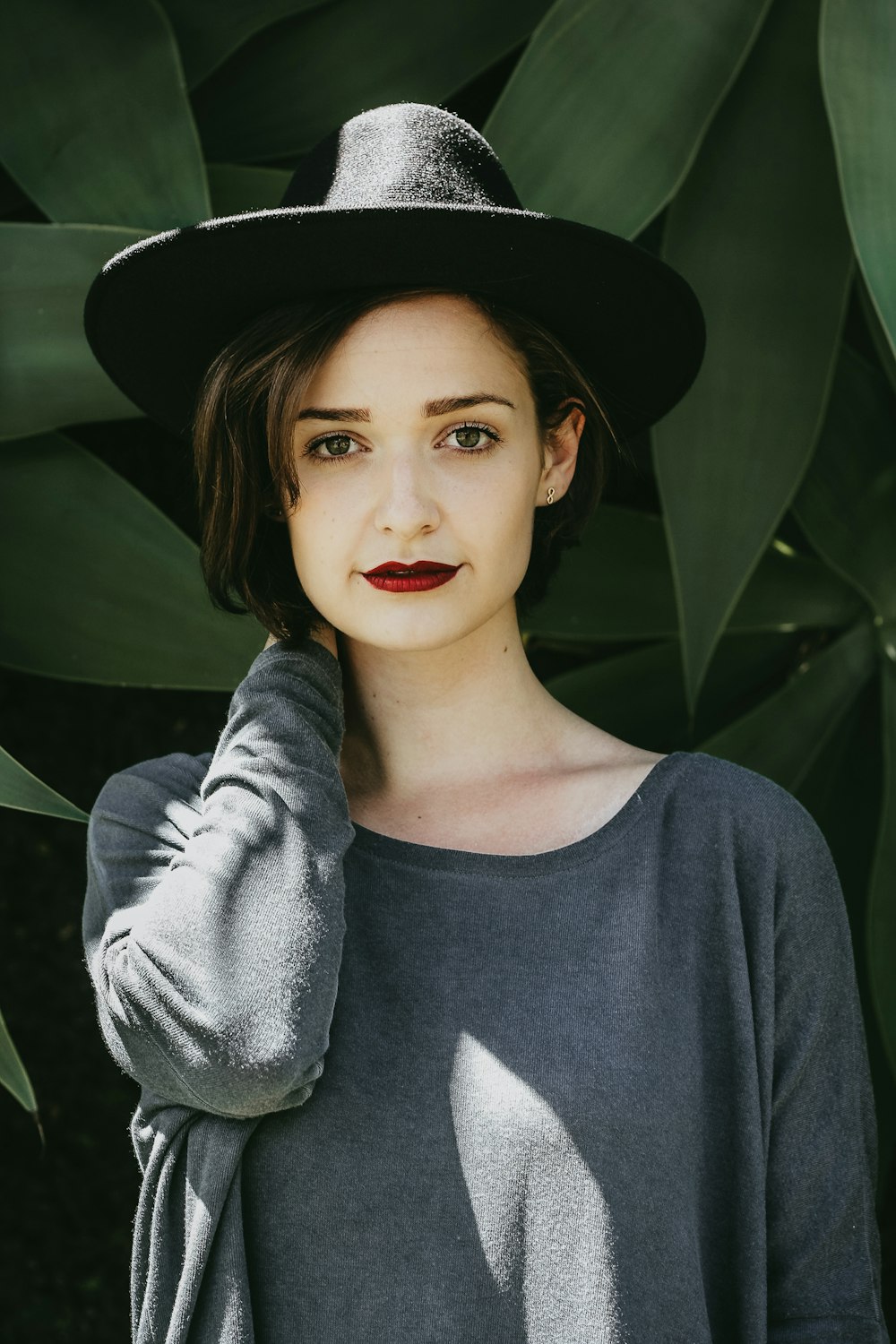 femme debout près des arbres portant un chapeau noir