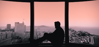 silhouette of person sitting on building's window