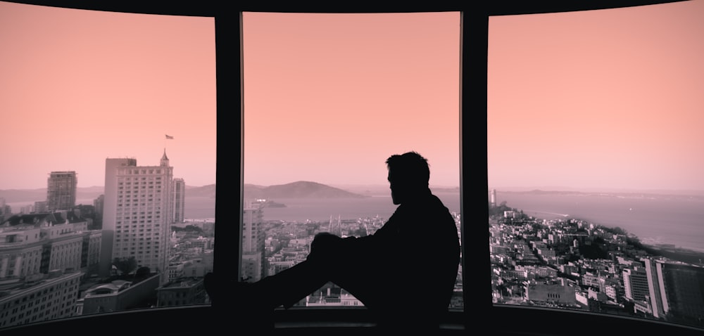 silhouette of person sitting on building's window