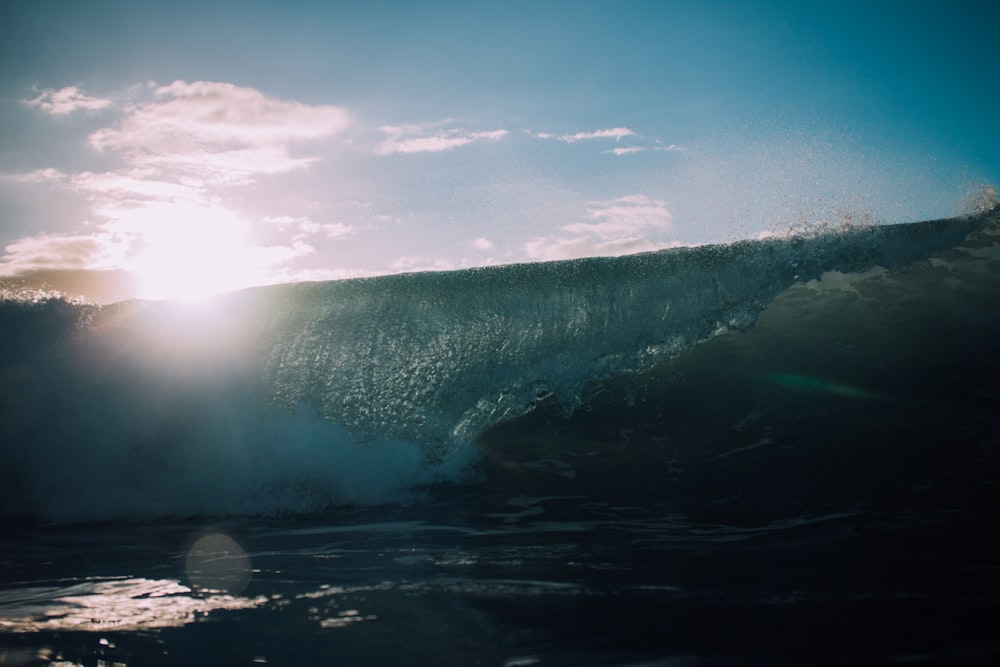 the sun is shining behind a wave in the ocean