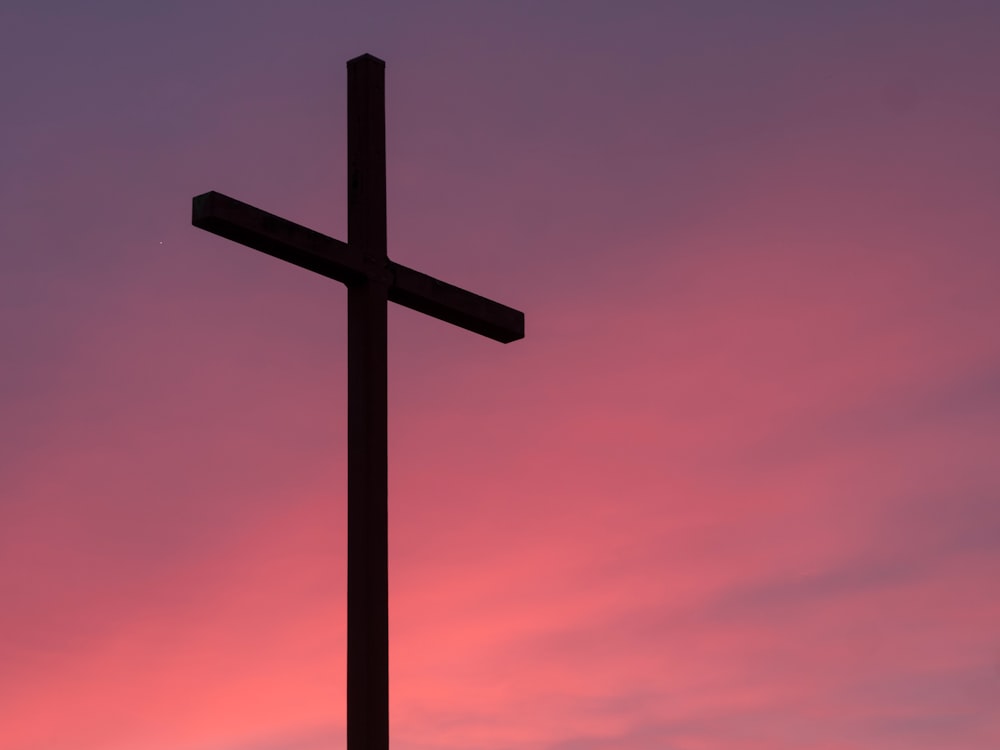 A cross against a pink and purple sky