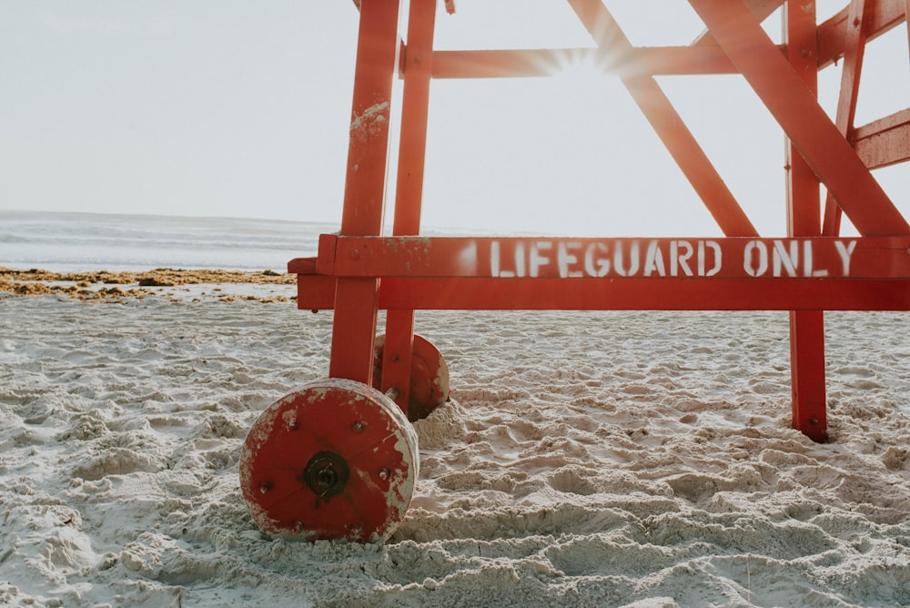 red lifeguard post near shoreline during daytime