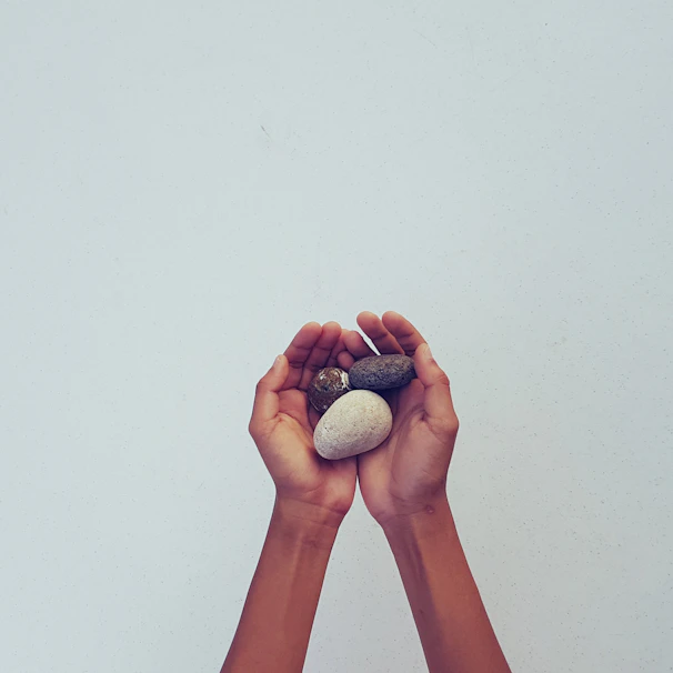 A close-up of hands gently holding a smooth stone, symbolizing grounding and calm