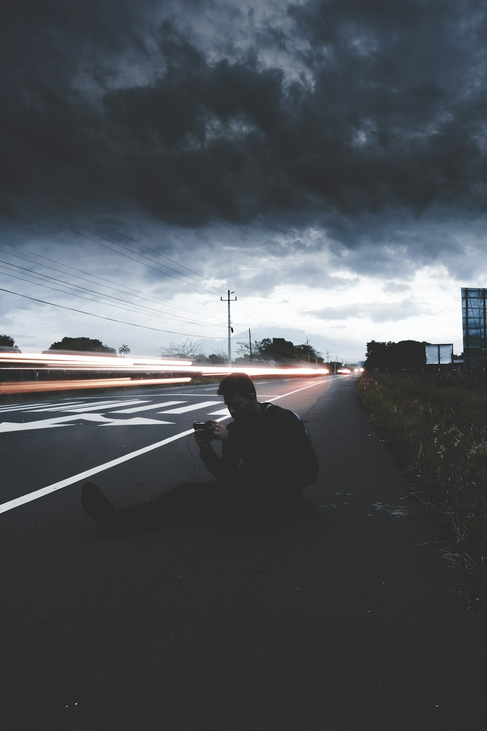 man sitting on road in time lapse photography