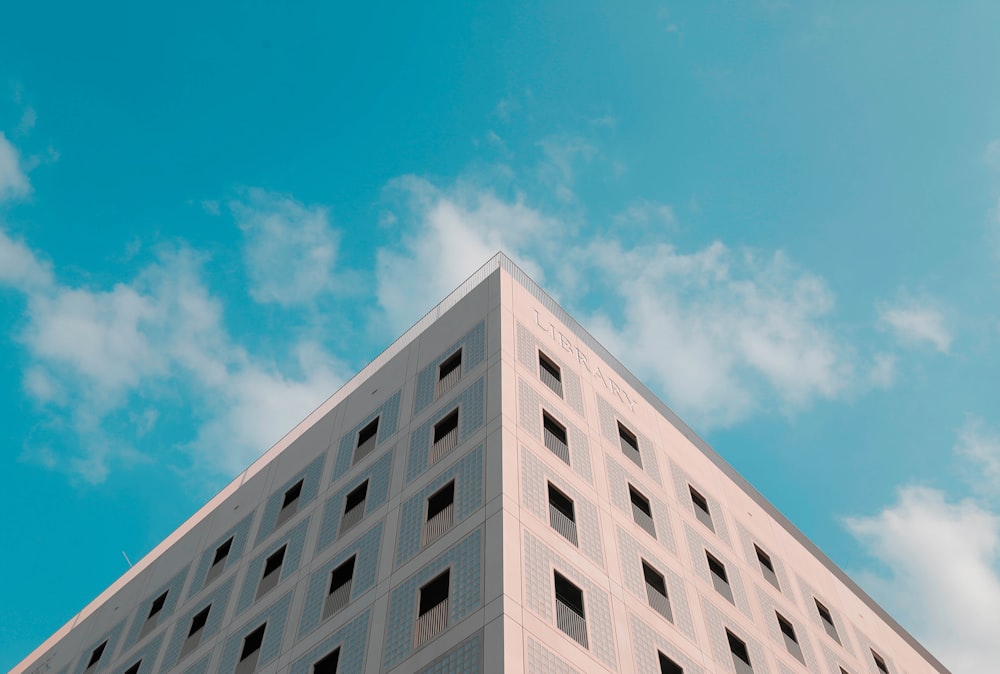 fotografia a fuoco superficiale dell'edificio della biblioteca sotto cieli nuvolosi blu e bianchi durante il giorno