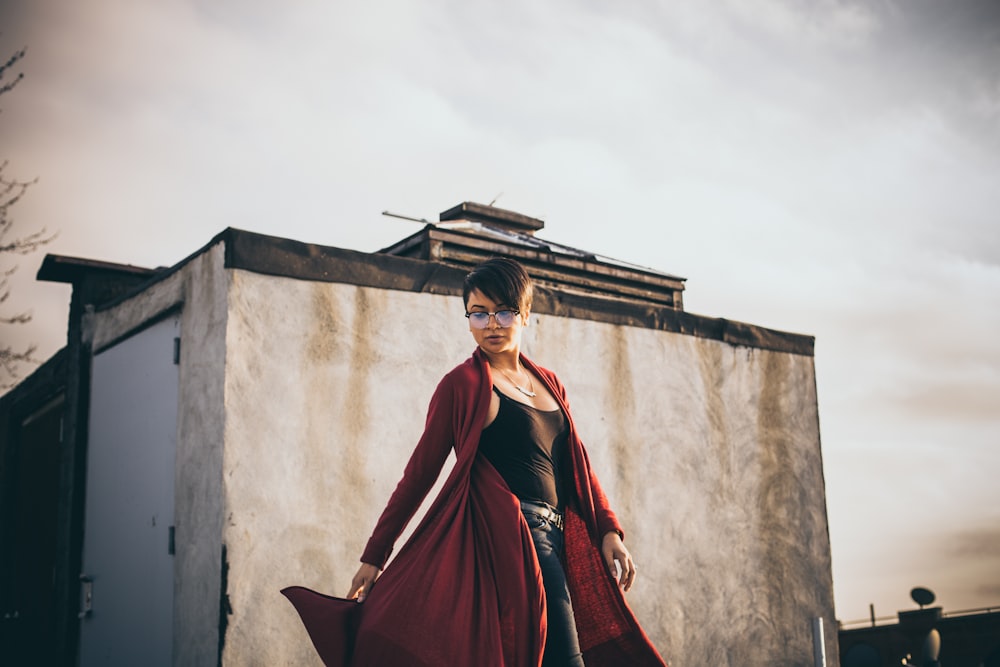 woman wearing red coat standing in front of white concrete structure