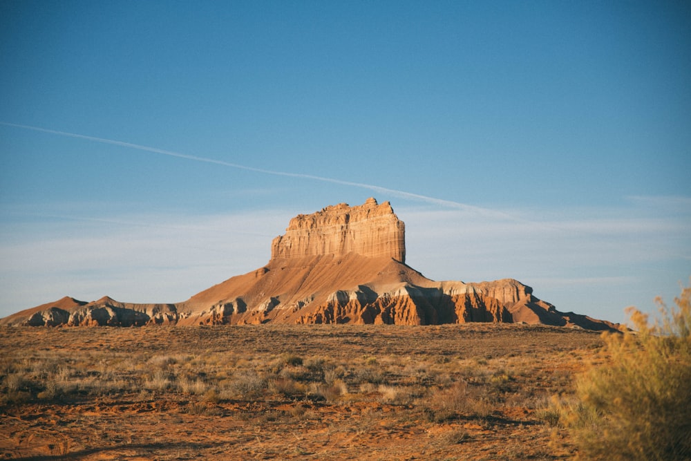 brown rock formation on top of hill under blue sky at daytime