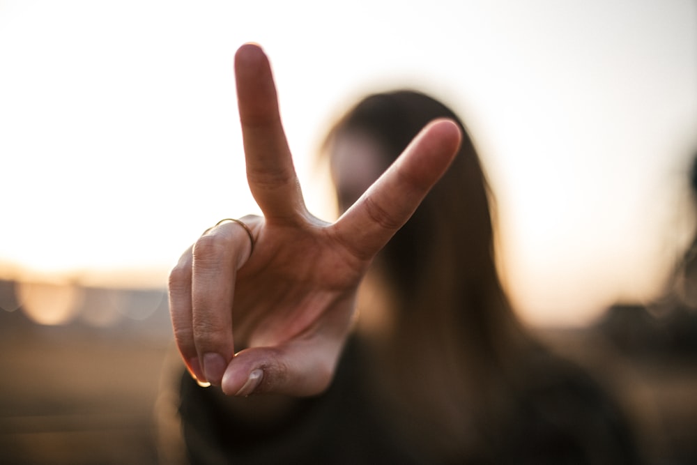Fokusfotografie der Frauenhand mit Peace-Zeichen