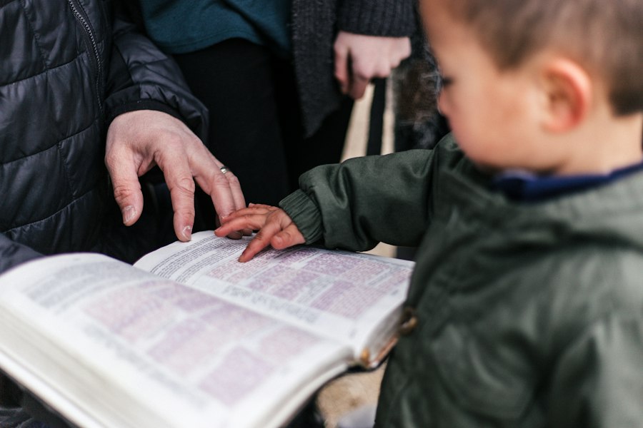 Niño leyendo la Biblia junto a un adulto