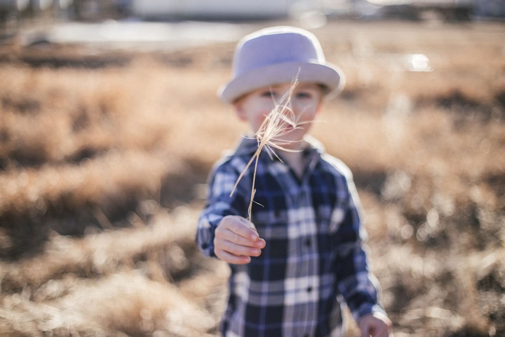 selective focus photography of boy standing near outdoor during daytime