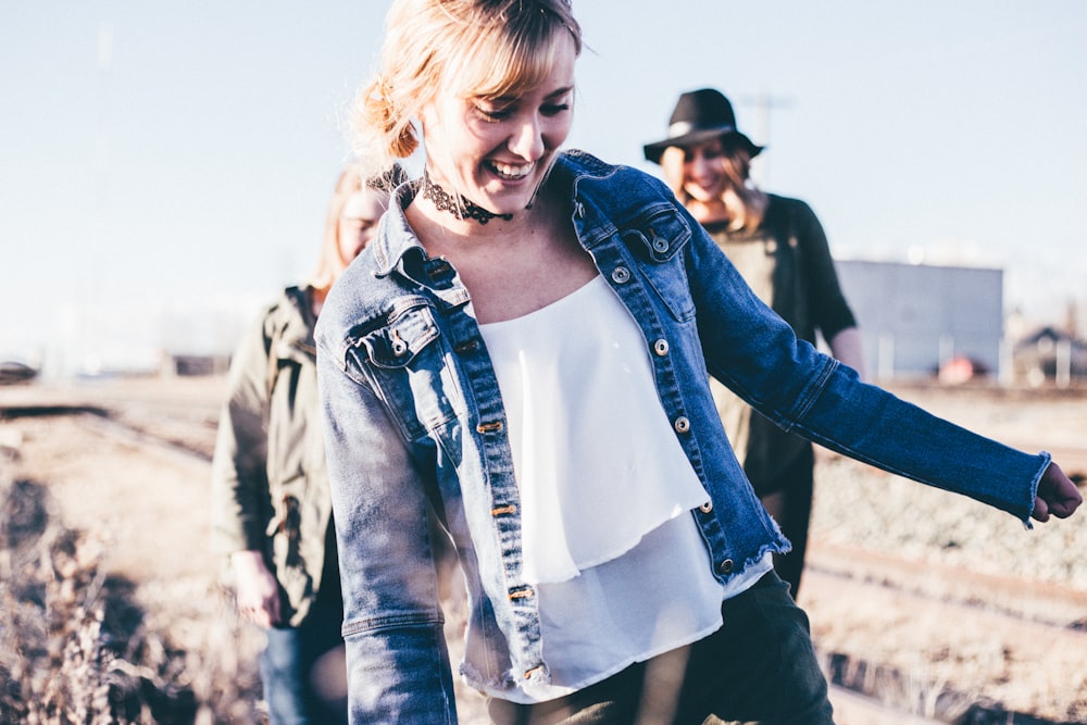 girl smiling wearing blue denim button-up jacket standing outdoor during daytime