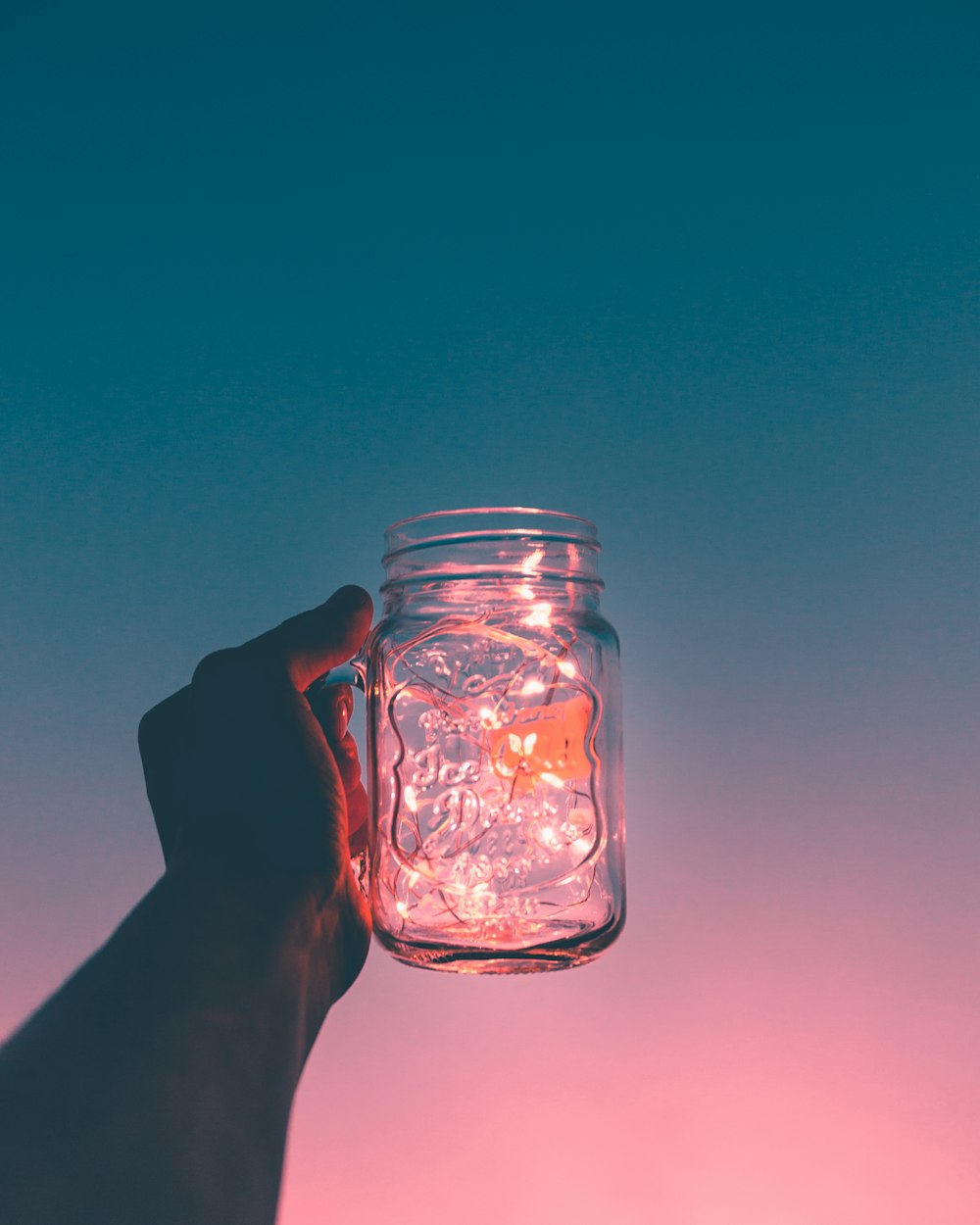 person holding clear glass mug jar